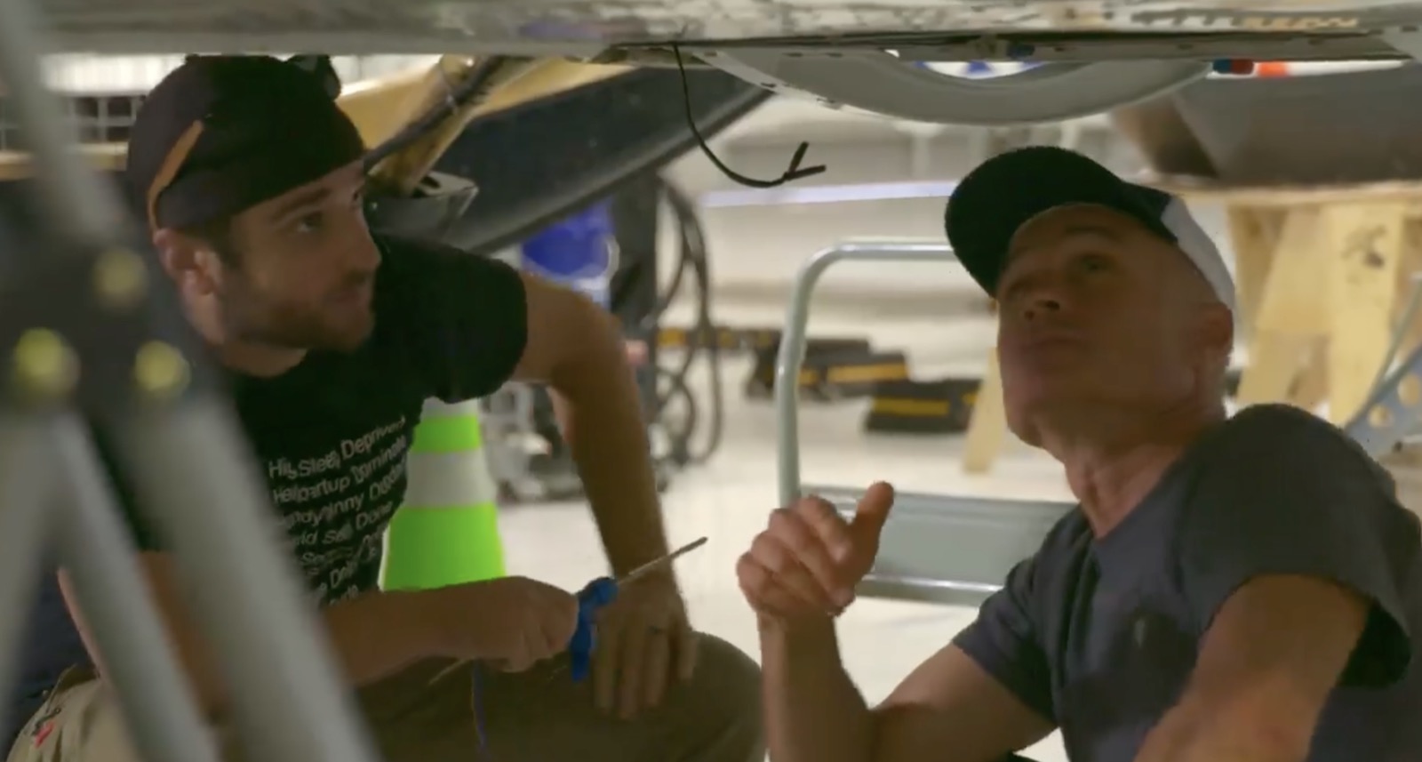 Hands-on aircraft subsystem work under the fuselage.